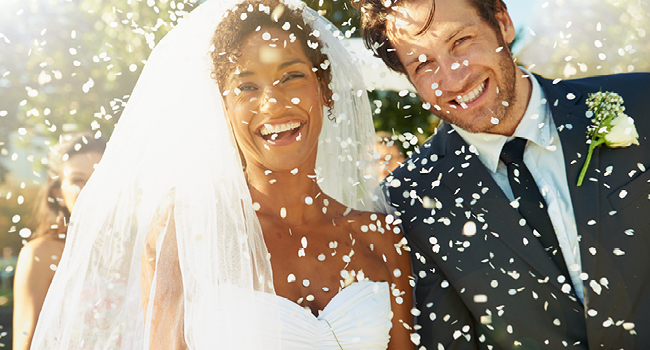 Bride and Groom smiling while walking under falling confetti